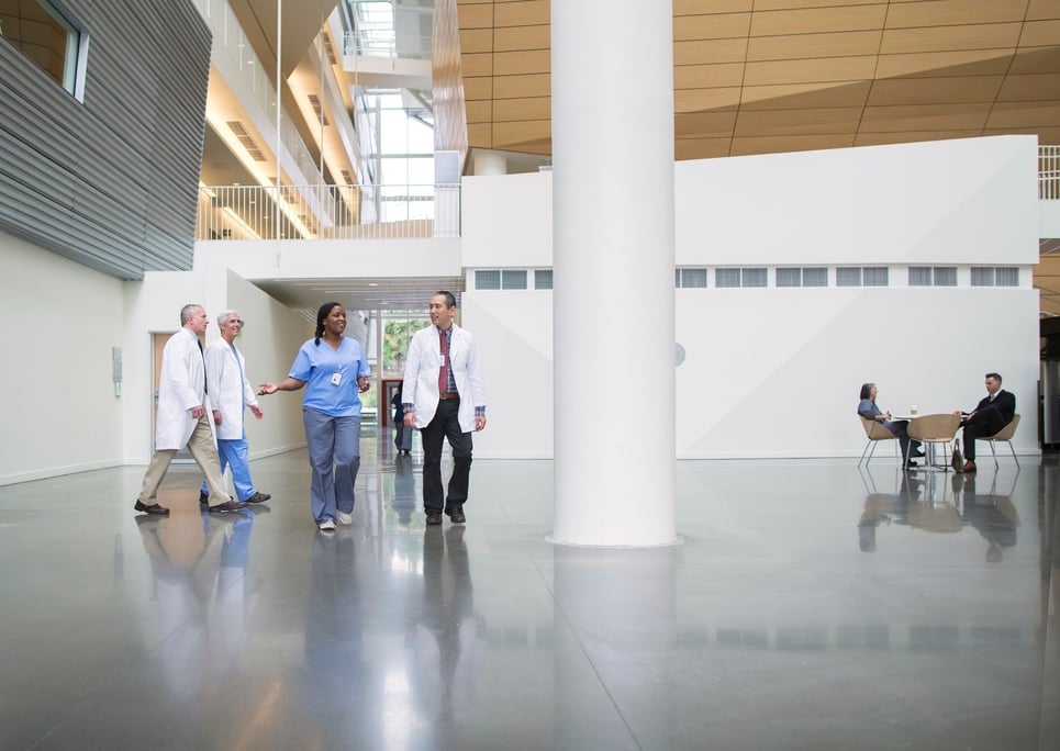 Bright hospital lobby with hospital professionals and visitors quickly passing by